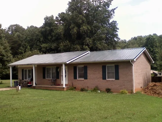 Gray metal roof on a brick ranch house with a side carport in Alexandria